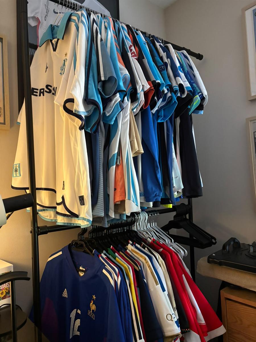 Maillots de foot rangés sur un portant, dans une pièce à vivre sèche et tempérée